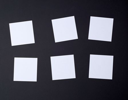 empty white small square sheets of paper on a black background. Mockup template. Business background.