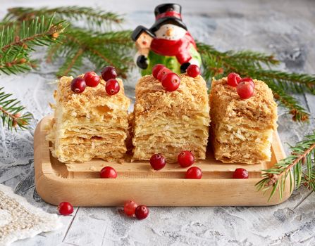 pieces of baked layer of cake Napoleon with butter cream on a wooden board, close up