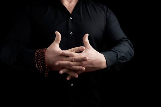 man in a black shirt crossed his fingers and performs the Vajrapradama Mudra. Male hand sign.