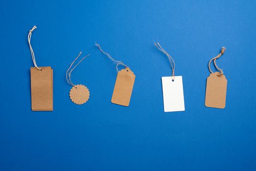 set of paper brown and white blank tags on a rope on a blue background. Vintage flat business template with paper brown tag empty for packaging design. Price tag label
