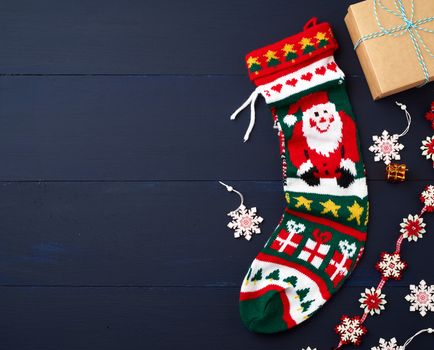 bright knitted christmas sock and decor on a blue wooden background from boards. Christmas decoration background, copy space