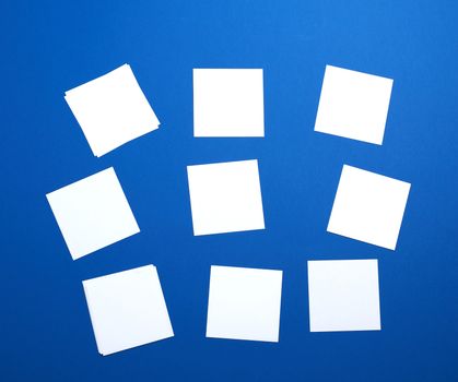 empty white small square sheets of paper on a blue background. Mockup template. Business background.
