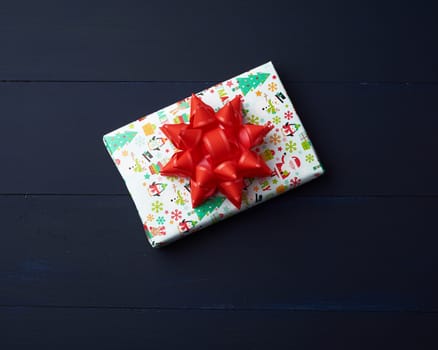 gift wrapped in multi-colored paper on a blue wooden background, festive backdrop, top view, copy space