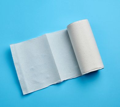 twisted roll of white paper towel on a blue background. Paper sheet. Household equipment. White napkin.