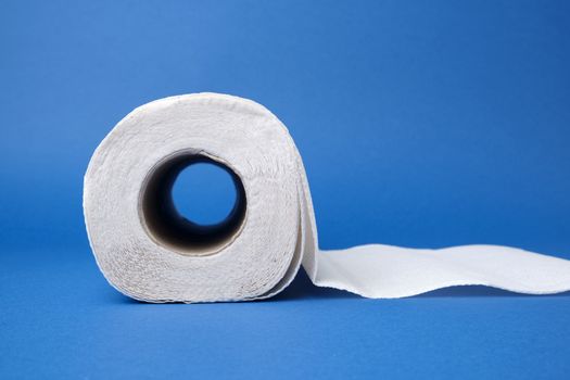 twisted roll of white paper towel on a blue background. Paper sheet. Household equipment. White napkin, close up