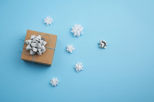 brown square box with a gift tied ribbon with a bow on a blue background, top view, empty place for an inscription