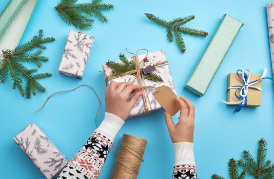 gift wrapped in pink paper and tied with a brown rope, two female hands tied an empty tag for inscription, congratulation concept