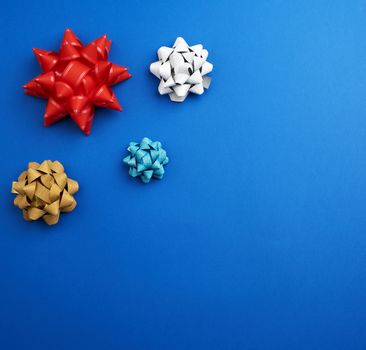 knotted multi-colored ribbon bows on a blue background, top view, copy space
