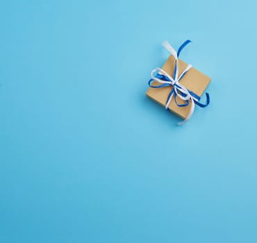 brown cardboard gift square box, bows on a blue background, top view. Festive concept, copy space