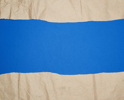 torn brown sheet of paper on a blue background, full frame, close up