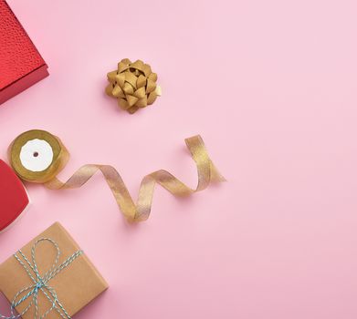 square gift boxes decorated with ribbons and bows on a pink background, top view, place for text