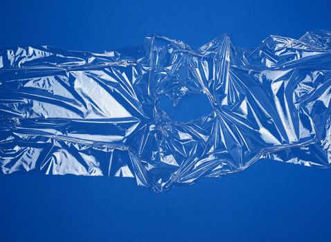 texture of a transparent stretching plastic film for packaging products on a blue background, full frame, close up