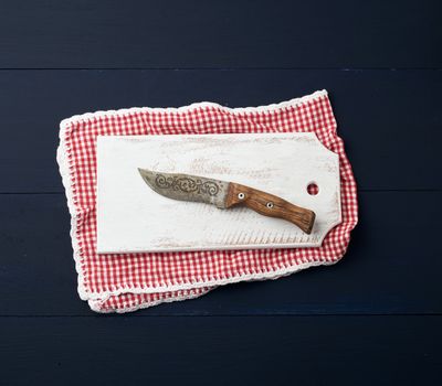 empty white wooden rectangular cutting board and knife, top view, blue wooden background 
