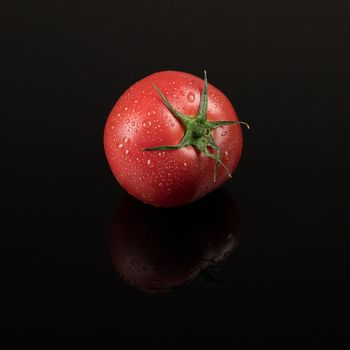 fresh wet tomato on black background with reflection