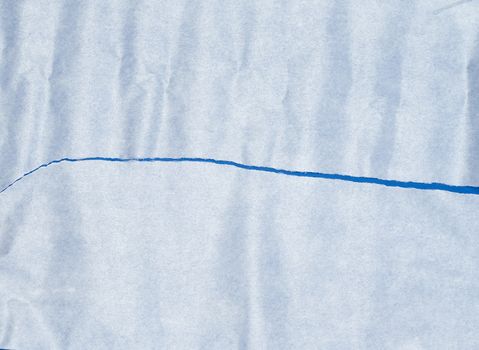 torn piece of white parchment paper on a blue background, close up