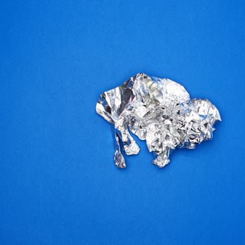 piece of crumpled foil on a blue background, close up