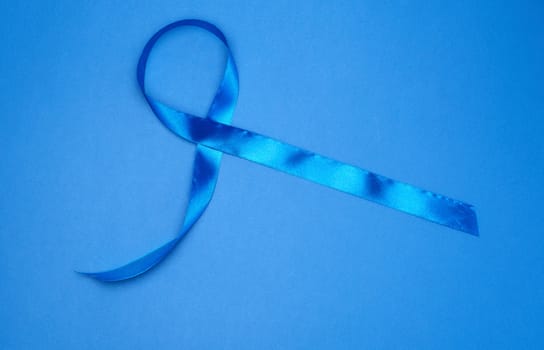 blue silk thin ribbon twisted on a blue background, top view