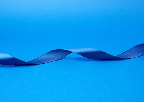 blue silk thin ribbon twisted on a blue background, trendy classic color, close up
