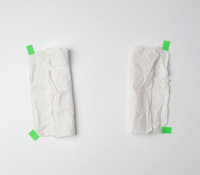 crumpled dirty white piece of paper towel glued with green paper velcro on a white background, place for text