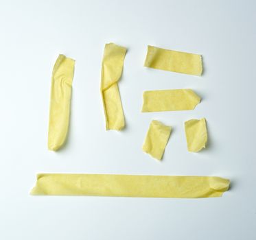 set of various pieces of yellow sticky paper tape on a white background, close up