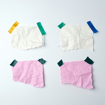 blank crumpled sheets of paper glued with rubber colored adhesive tape on a white background, copy space