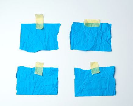 empty blue crumpled pieces of paper glued with duct tape on a white background