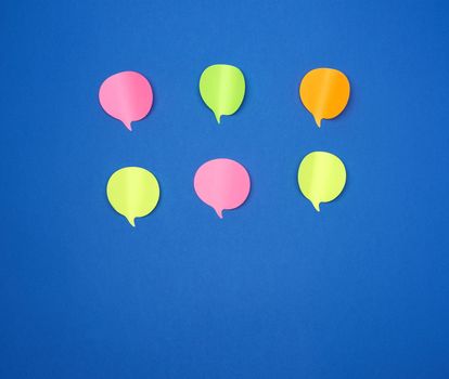 multicolored empty paper stickers in the form of clouds on a blue background, copy space