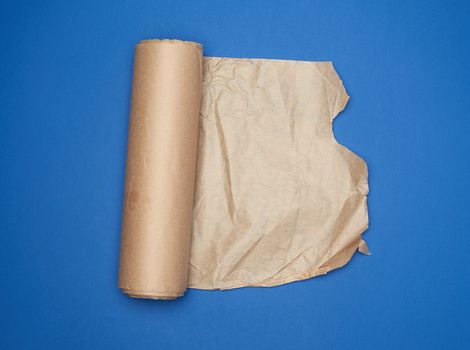 roll of brown parchment paper on a blue background, copy space, top view