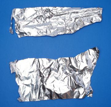 crumpled silver foil sheet, full frame, blue background 