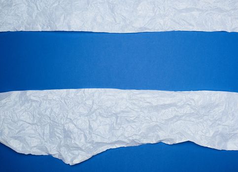 blue background with white crumpled torn paper elements, place for writing op in the middle, template