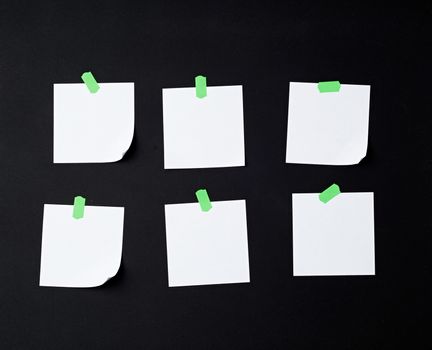 set of square white blank sheets of paper glued with green sticky paper on black background