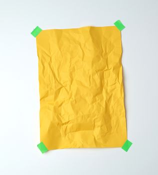 empty yellow crumpled sheet of paper glued with green sticky pieces of paper on a white background, place for text