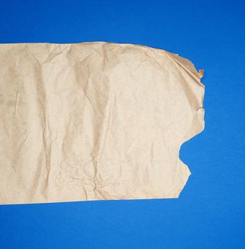 torn brown sheet of paper on a blue background, full frame, close up