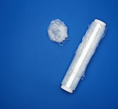 big roll of wound white transparent film for wrapping food, dark blue background, top view