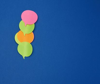 multicolored empty paper stickers in the form of clouds on a blue background, copy space