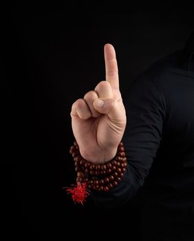 hand of an adult male shows a dragon tooth mudra on a dark background