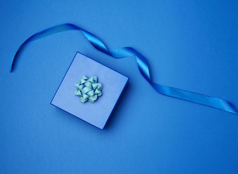 cardboard gift square box, bows, ribbons for packaging on a dark blue background, top view, trend colors