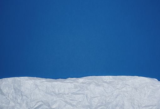 blue background with white crumpled torn paper elements, place for writing op in the middle, template