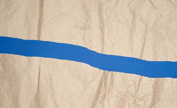 torn brown sheet of paper on a blue background, full frame, close up