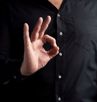 man in a black shirt shows the ok symbol with his right hand, approval concept