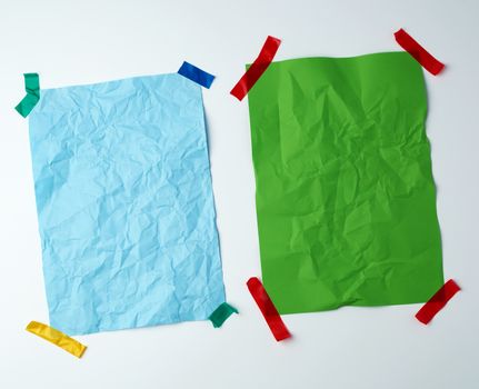 two blank crumpled sheets of paper glued with rubber colored adhesive tape on a white background, copy space