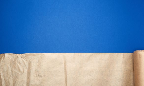 untwisted roll of brown parchment paper on a blue background, copy space