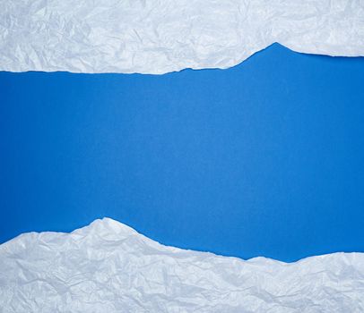 blue background with white crumpled torn paper elements, place for writing op in the middle, template