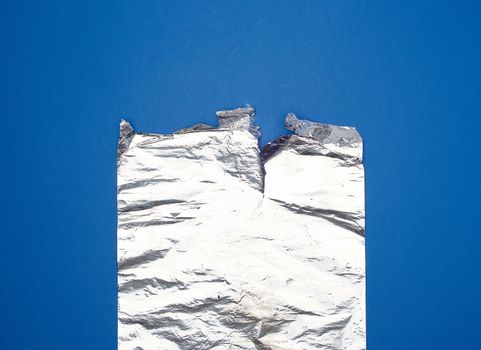 gray foil for baking and packaging food on a blue background, torn edge
