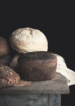 various baked rolls of rye bread on a wooden surface, vintage toning, close up