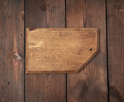 very old empty wooden rectangular cutting board, top view, brown wooden background 