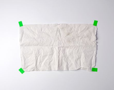 crumpled dirty white piece of paper towel glued with green paper velcro on a white background, place for text