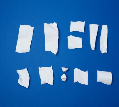 set of various pieces of torn white crumpled paper on a blue background, close up