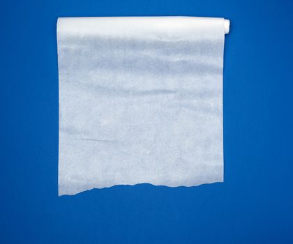 unwound white parchment baking paper on a blue background, top view