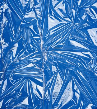 texture of a transparent stretching plastic film for packaging products on a blue background, full frame, close up